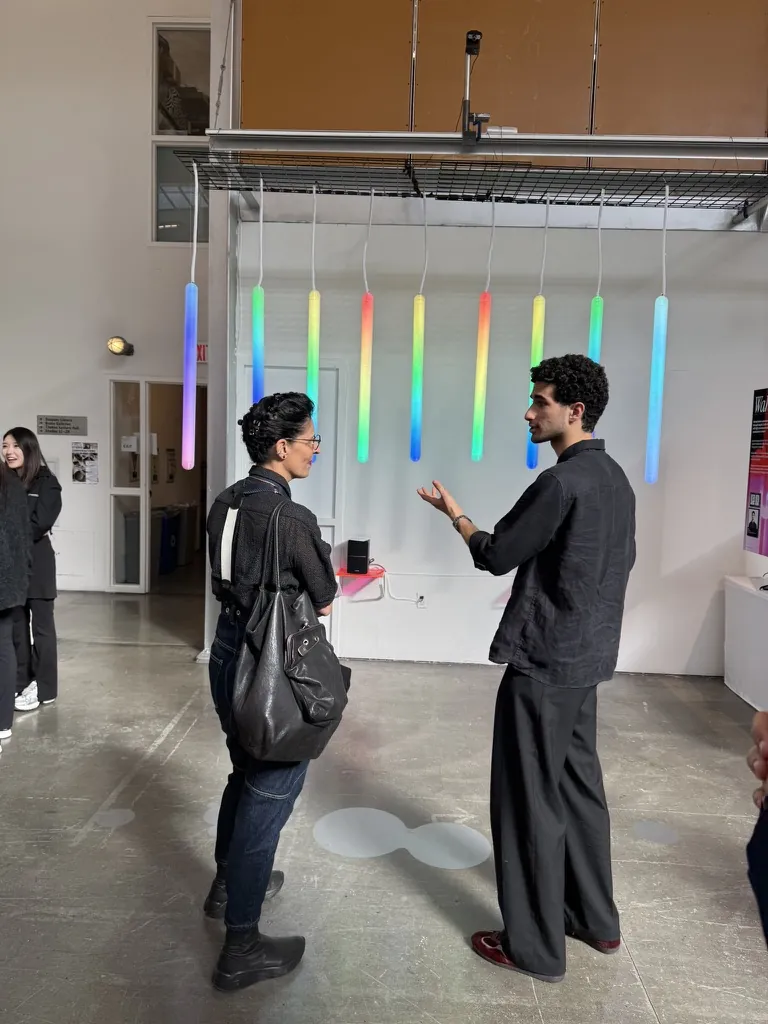 Abed walking a visitor through Wahaj, the tubes glowing in a rainbow behind them